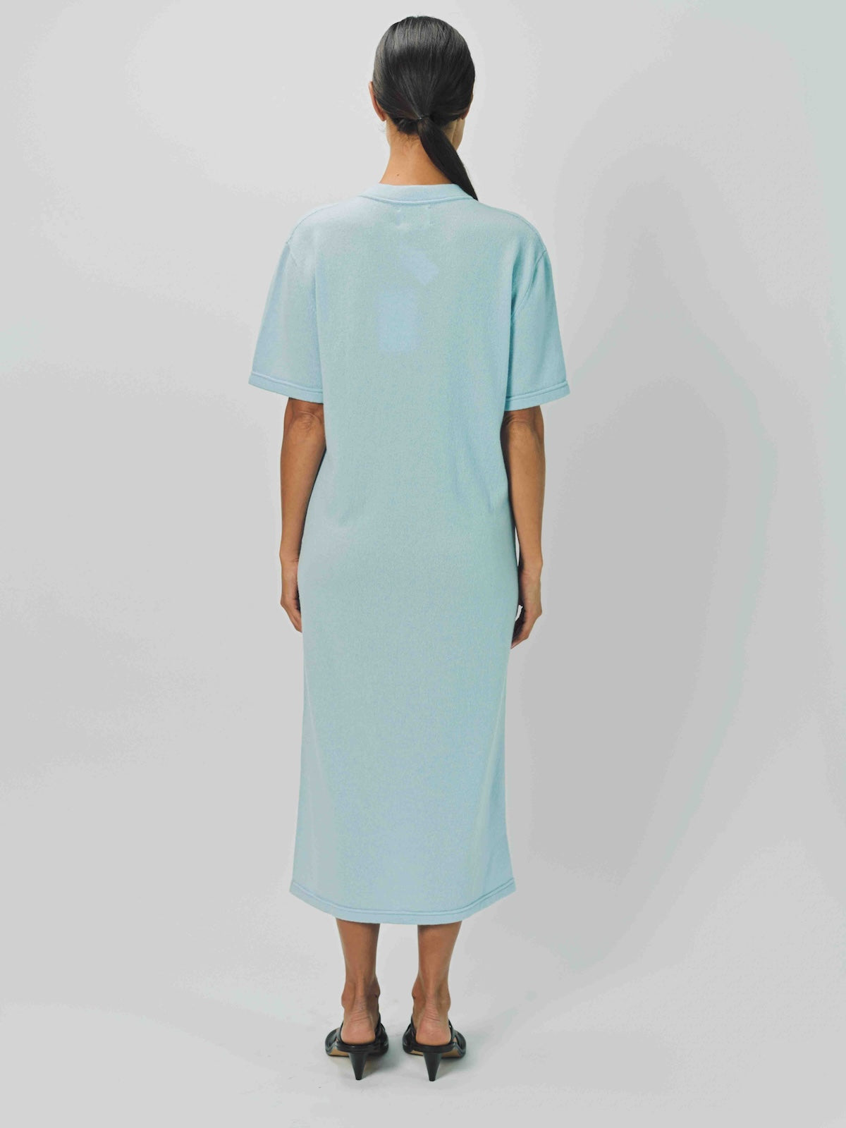 Back view of cielo cashmere long t-shirt dress on model wearing sandals, against a white background.
