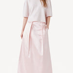 Front view of pink duchesse bogart long skirt on model wearing pink top, against a white background.