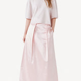 Front view of pink duchesse bogart long skirt on model wearing pink top, against a white background.