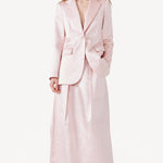 Front view of pink duchesse bogart long skirt on model wearing pink blazer, against a white background.