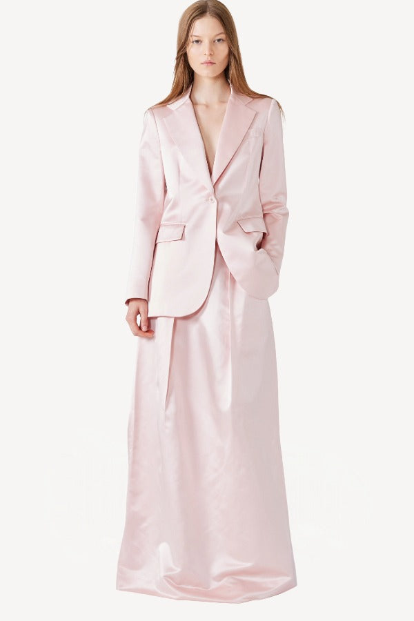 Front view of pink duchesse bogart long skirt on model wearing pink blazer, against a white background.