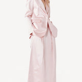 Side view of pink duchesse bogart long skirt on model wearing pink blazer, against a white background.