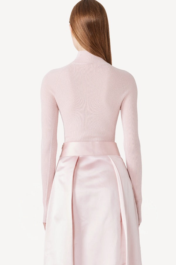 Back view of pink duchesse bogart long skirt on model wearing pink top, against a white background.