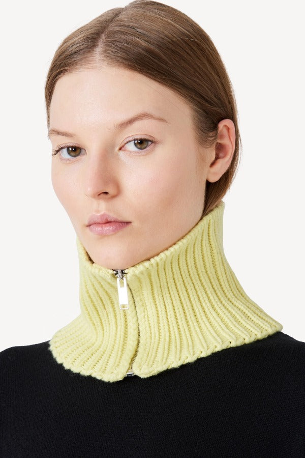 Front view of yellow knit cashmere collar scarf on model wearing black sweater, against a white background.