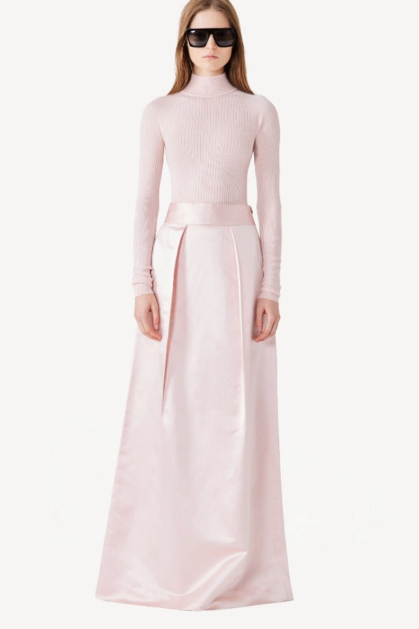 Front view of light pink l/s high neck sweater on model wearing a pink skirt, against a white background.