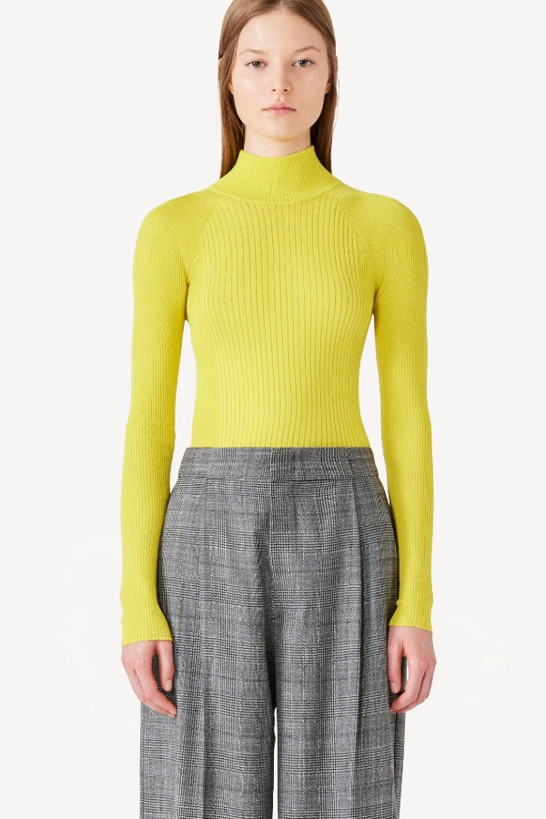 Front view of yellow l/s cashmere high neck sweater on model wearing grey pants, against a white background