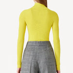 Back view of yellow l/s cashmere high neck sweater on model wearing grey pants, against a white background.