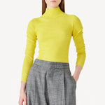 Alternate front view of yellow l/s cashmere high neck sweater on model wearing grey pants, against white background