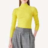 Alternate front view of yellow l/s cashmere high neck sweater on model wearing grey pants, against white background