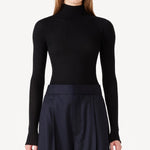 Front view of black l/s cashmere high neck sweater on model wearing navy pants, against a white background.