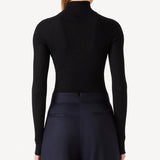 Back view of black l/s cashmere high neck sweater on model wearing navy pants, against a white background.