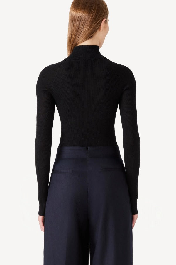 Back view of black l/s cashmere high neck sweater on model wearing navy pants, against a white background.