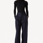 Front view of black l/s cashmere high neck sweater on model wearing navy pants, against a white background.