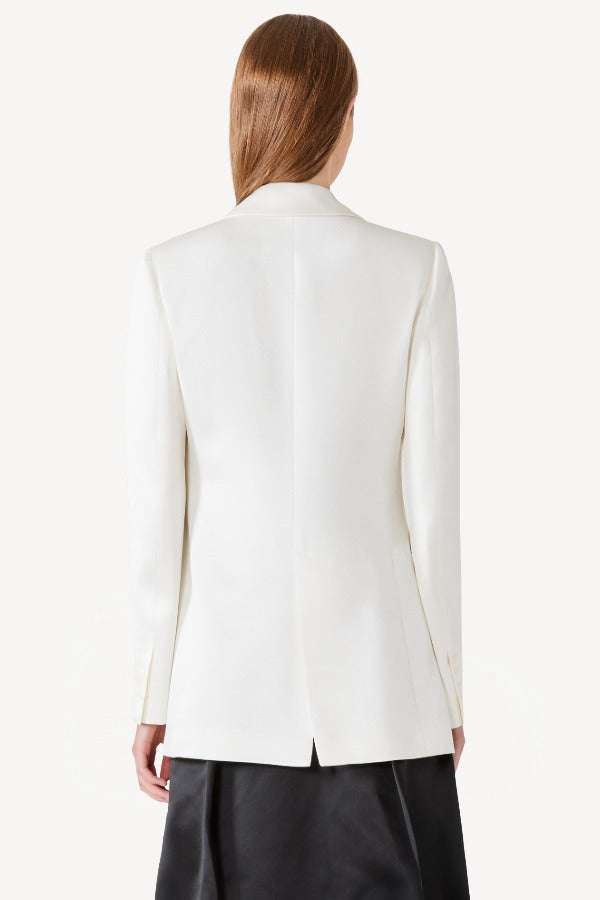 Back view of ivory l/s double satin andrea blazer jacket on model wearing black skirt, against a white background.