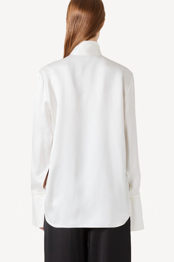 Back view of ivory l/s double satin shirt with scarf on model wearing black pants, against a white background.