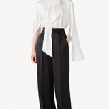 Front view of ivory l/s double satin shirt with scarf on model wearing black pants, against a white background.