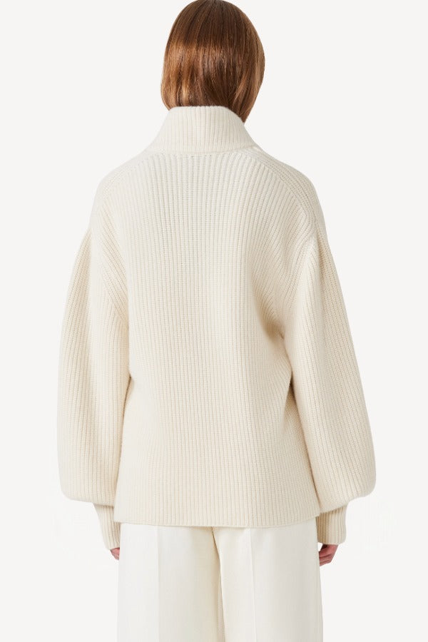 Back view of ivory gemma sweater on model wearing white pants, against a white background.