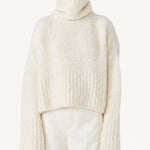 Front view of ivory l/s high neck cashmere sweater on model wearing white pants, against a white background.