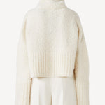 Back view of ivory l/s high neck cashmere sweater on model wearing white pants, against a white background.