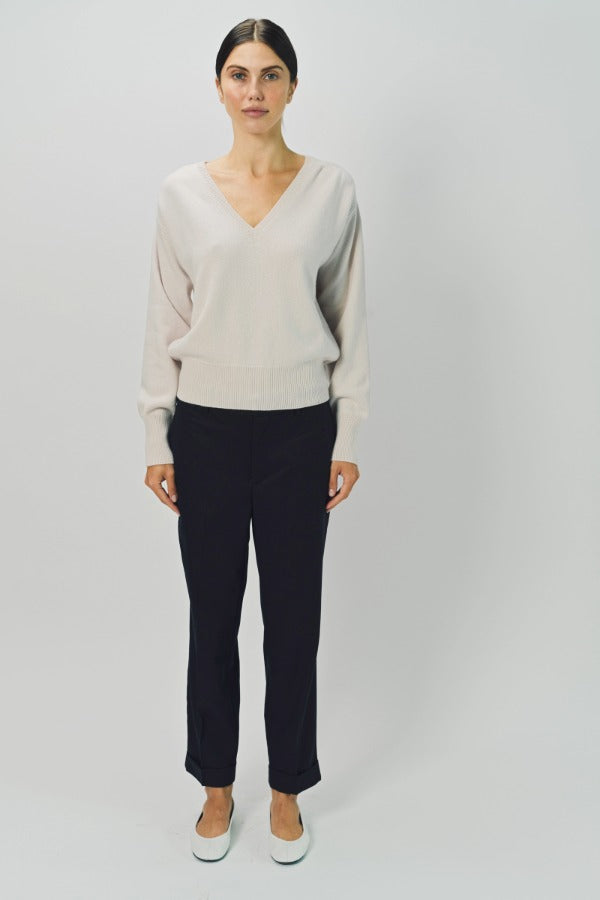 Front view of nude lavina v-neck cashmere sweater on model wearing black pants and flats, against a white background.