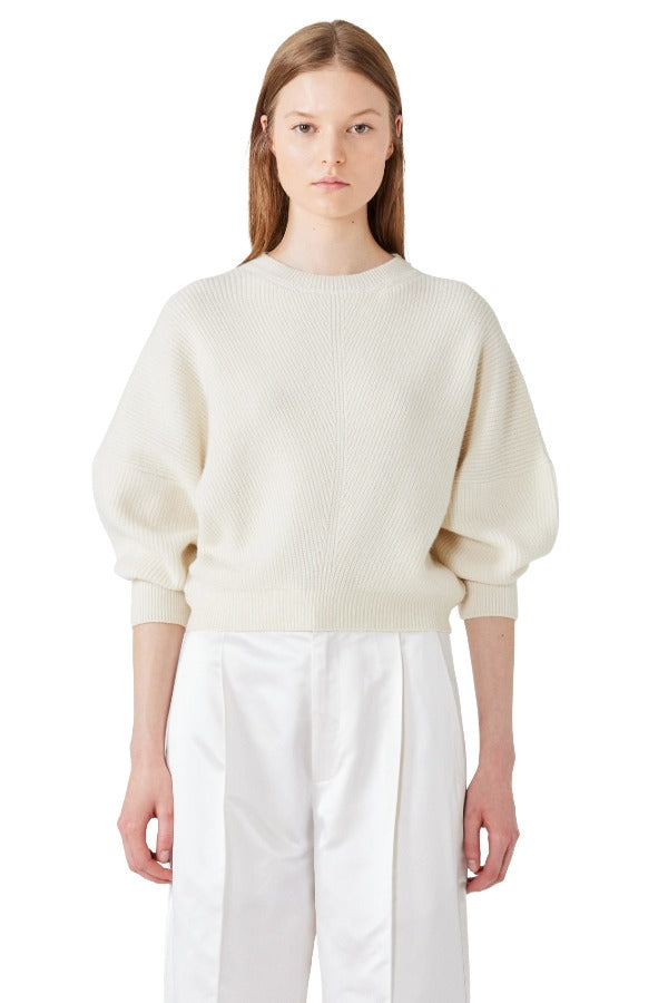 Front view of ivory mina cashmere bat wing sweater on model wearing white pants, against a white background