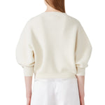 Back view of ivory mina cashmere bat wing sweater on model wearing white pants, against a white background.
