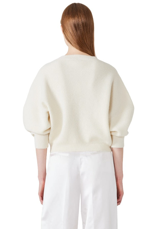 Back view of ivory mina cashmere bat wing sweater on model wearing white pants, against a white background.