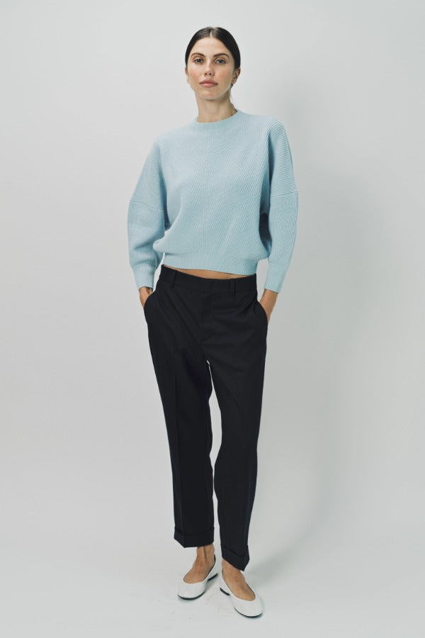 Front view of cielo mina cashmere bat wing sweater on model wearing black pants and flats, against a white background.