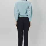 Back view of cielo mina cashmere bat wing sweater on model wearing bladck pants and flats, against a white background.