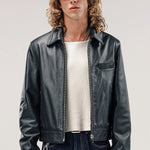 Front view of black ant de padovane jacket on model wearing white shirt and jeans, against a white background.