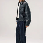 Side view of black ant de padovane jacket on model wearing white shirt, jeans and boots, against a white background.