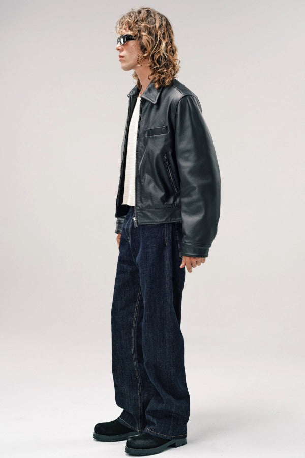 Side view of black ant de padovane jacket on model wearing white shirt, jeans and boots, against a white background.