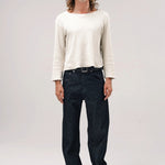 Alternate front view of black papi denim on model wearing white shirt and boots, against a white background.