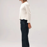 Side view of black big papi denim pants on model wearing white shirt and boots, against a white background.