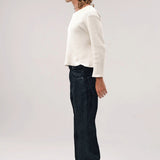 Side view of black big papi denim pants on model wearing white shirt and boots, against a white background.