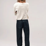 Back view of black big papi denim pants on model wearing white shirt and boots, against a white background,