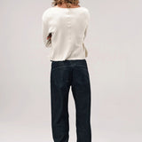 Back view of black big papi denim pants on model wearing white shirt and boots, against a white background,