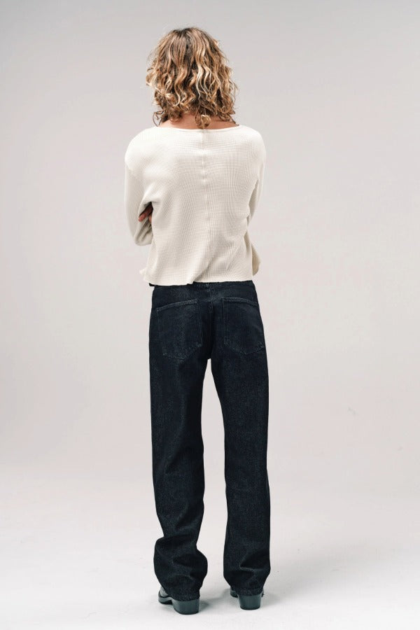 Back view of black big papi denim pants on model wearing white shirt and boots, against a white background,
