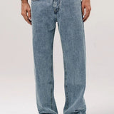 Front view of stone wash big papi denim pants on model wearing white shirt and boots, against a white background.