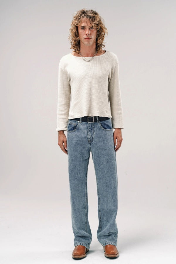 Alternate front view of stone wash big papi denim pants on model wearing white shirt and boots, against a white background.