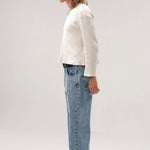 Side view of stone wash big papi denim pants on model wearing white shirt and boots, against a white background.