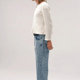 Side view of stone wash big papi denim pants on model wearing white shirt and boots, against a white background.
