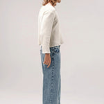 Alternate side view of stone wash big papi denim pants on model wearing white shirt and boots, against a white background.