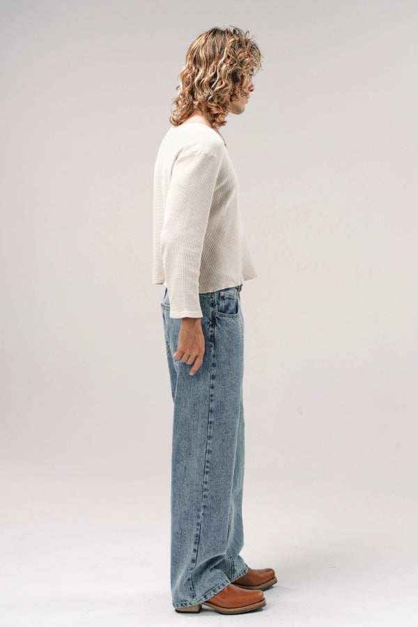 Alternate side view of stone wash big papi denim pants on model wearing white shirt and boots, against a white background.