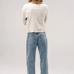 Back view of stone wash big papi denim pants on model wearing white shirt and boots, against white background.