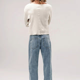 Back view of stone wash big papi denim pants on model wearing white shirt and boots, against white background.