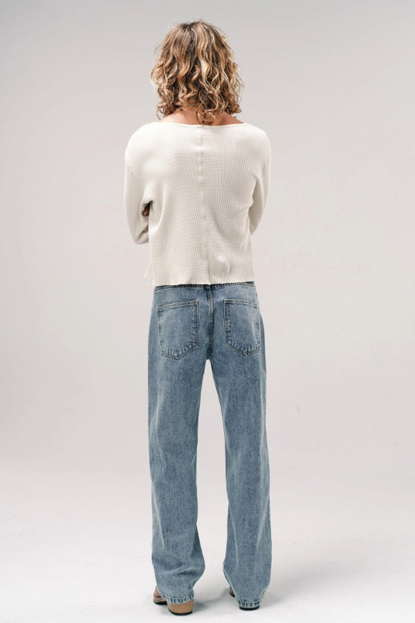 Back view of stone wash big papi denim pants on model wearing white shirt and boots, against white background.