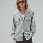 Front view of grey speckle church shirt on model wearing white shirt and grey pants, against a white background.