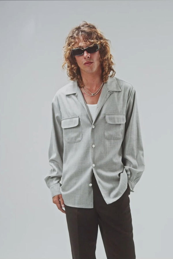 Front view of grey speckle church shirt on model wearing white shirt and grey pants, against a white background.