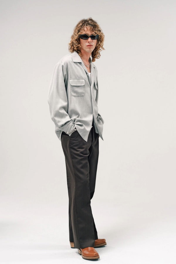 Side view of grey speckle church shirt on model wearing white shirt, grey pants and boots, against a white background.